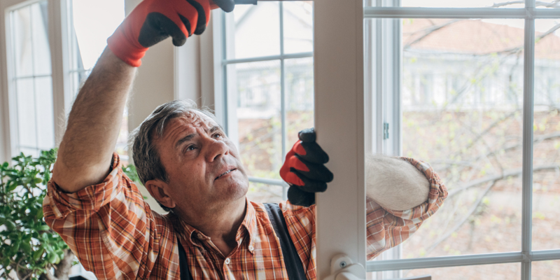 En ældre tømrer, der reparerer en dør